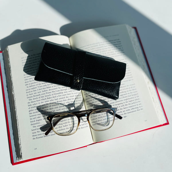 Black Leather Glasses Case with ace and tate glasses on a book