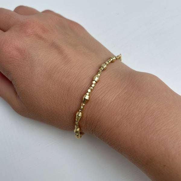 Gold bracelet on a wrist against a white background