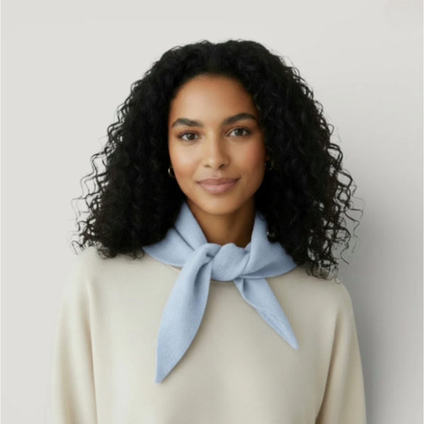 Woman wearing a light blue scarf around her neck against a plain background