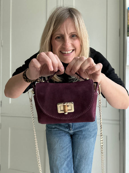 Woman holding a burgundy handbag with a white door in the background