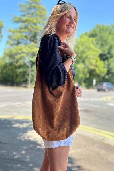 Woman holding a brown tote bag outdoors on a sunny day