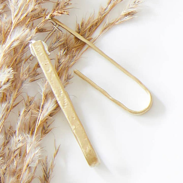 Hammered brass open hoop stud earrings 
on a light background with dried grasses.