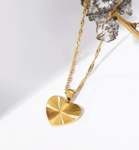 Gold necklace with a textured heart pendant on a white background
