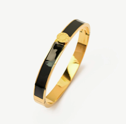 Gold and black enamel bangle on a white background