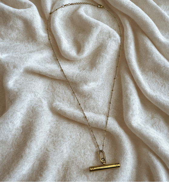 gold T-Bar pendant on a satellite chain on a cream velvet background