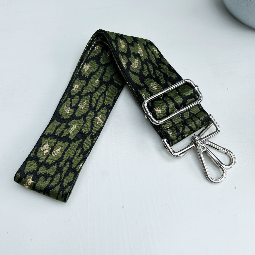 Green patterned strap with metal buckle and clip on a light gray background