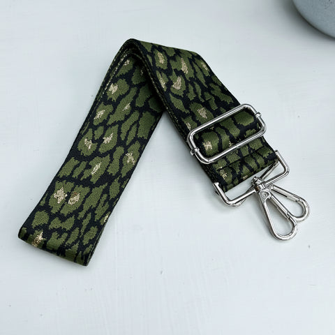 Green patterned strap with metal buckle and clip on a light gray background