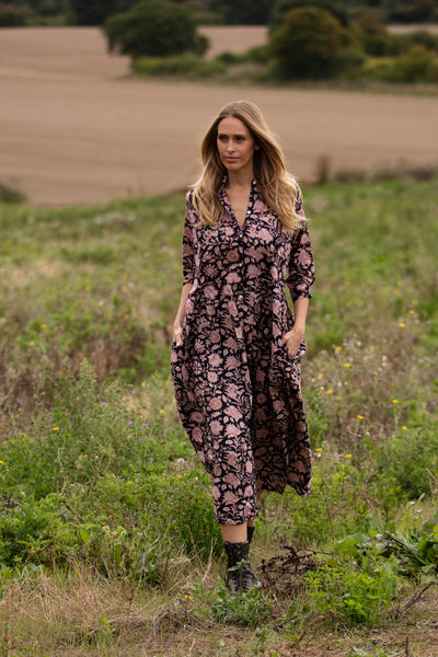 woman in a black floral dress standing in a field