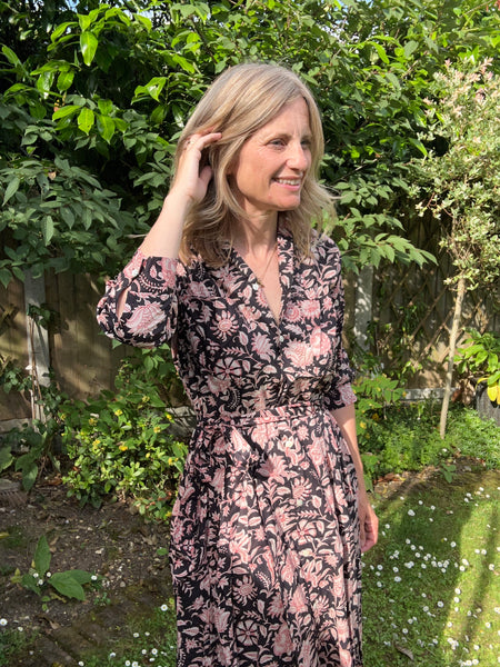 Women in a black floral shirt dress standing in a garden