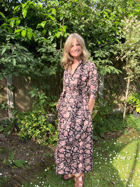 Women in a black floral shirt dress standing in a garden