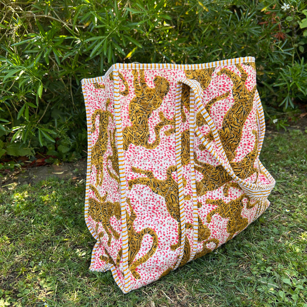 Leopard print cotton bag with striped handles on the grass