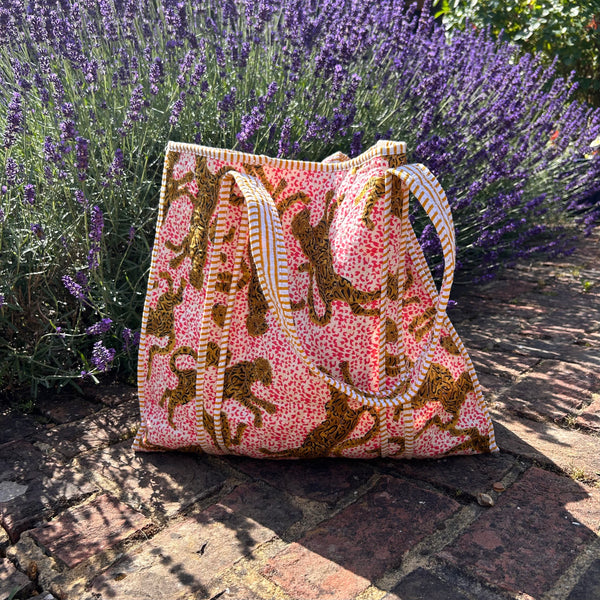 Pink and brown leopard print patterned bag on a stone path with lavender in the background