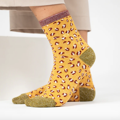 Yellow sock with a leopard print pattern worn by a person on a white background