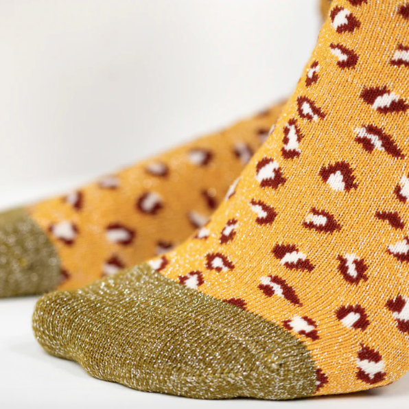 Pair of socks with a yellow and brown leopard print pattern on a white background