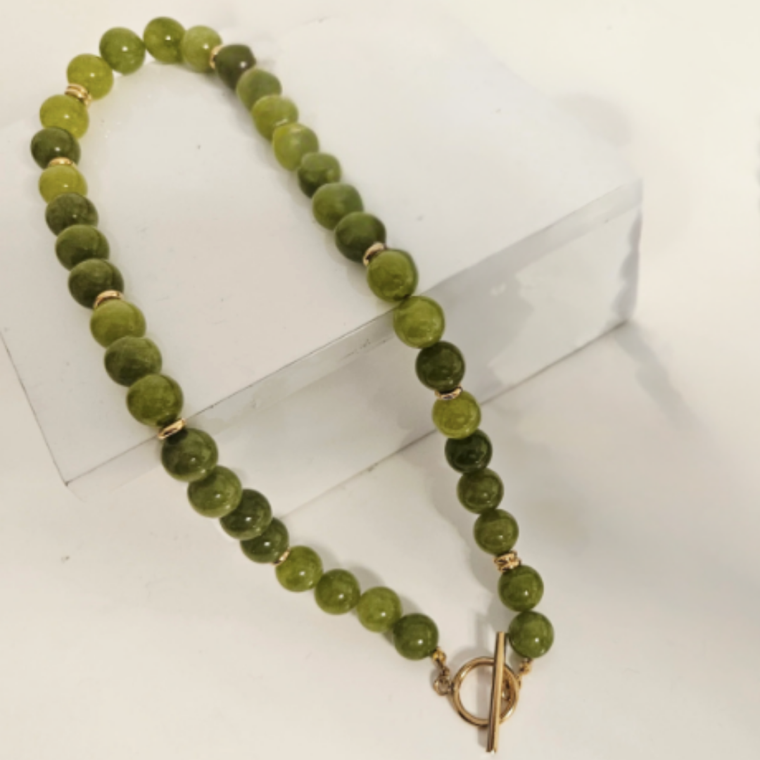Green quartz beaded necklace with a gold t-bar clasp on a white background