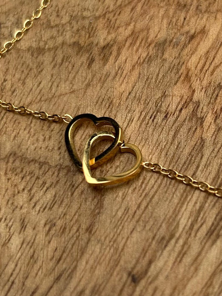 close up of two gold hearts interlinked on a wooden backround