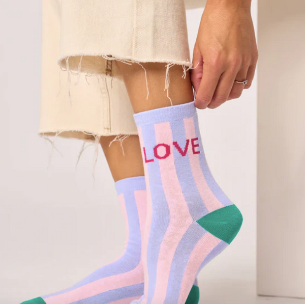 Person wearing colorful striped socks with 'LOVE' text on a neutral background