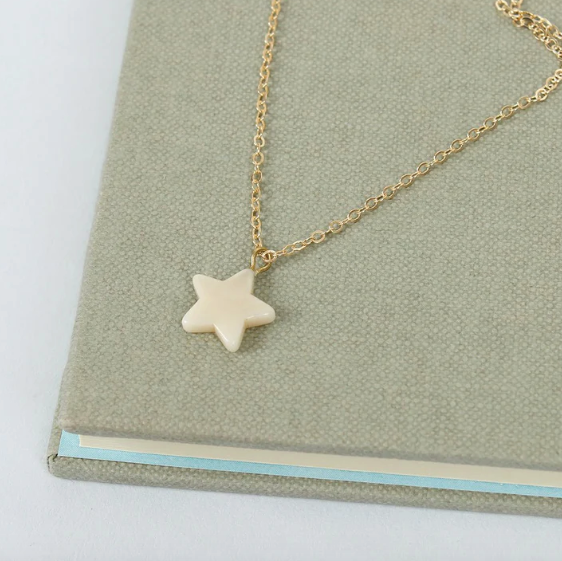 Gold necklace with a star-shaped pendant on a green surface