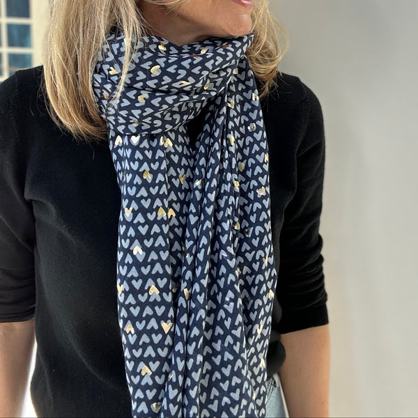 Woman wearing a blue heart patterned scarf with a neutral background