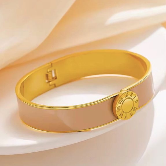 Gold and nude enamel bracelet on a soft beige fabric background