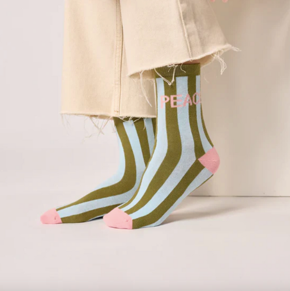 Colorful striped socks with 'PEACE' text worn by a person on a light background