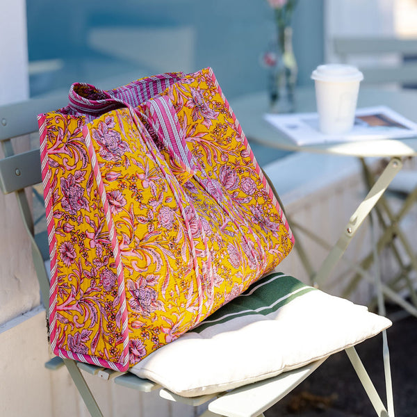 Colorful yellow and pink patterned bag on a chair with a blurred outdoor background