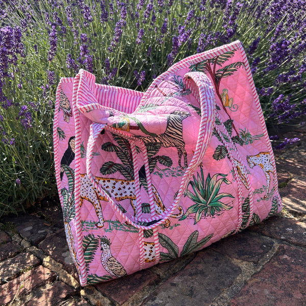 Pink quilted tote bag with animal pattern on a stone surface with lavender in the background