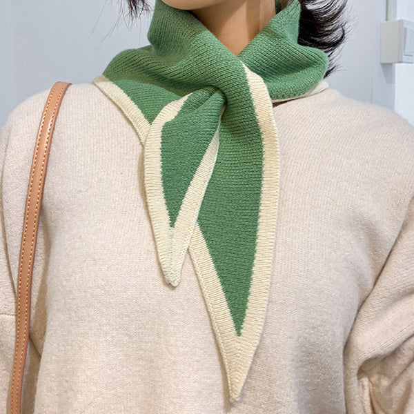 Woman wearing a green and white knitted scarf with a neutral background