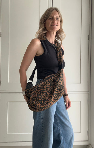 Woman holding a leopard print bag in front of a white door