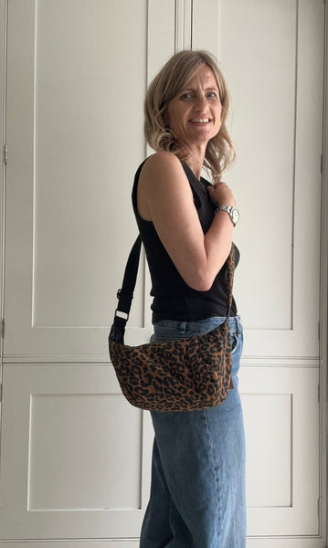 Woman holding a leopard print bag in front of a white door