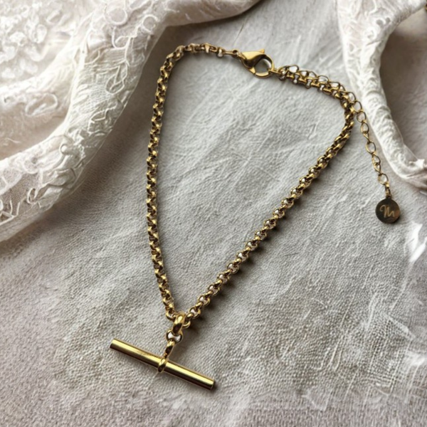 gold T-bar pendant bracelet on a crea velvet background