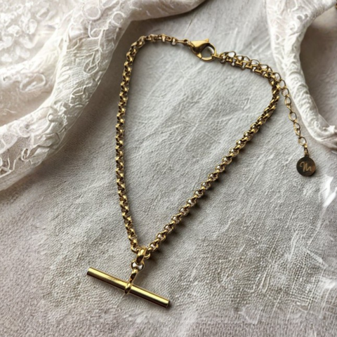 gold T-bar pendant bracelet on a crea velvet background