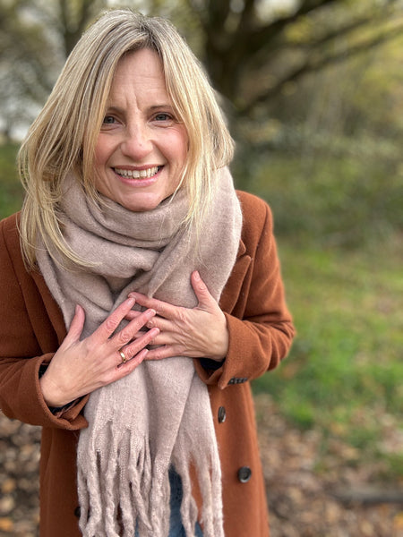 Woman wearing a brown coat and beige scarf outdoors