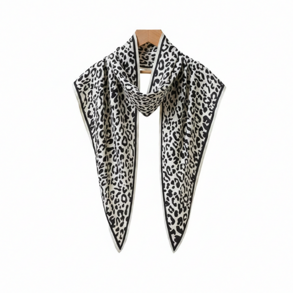A black and white leopard print scarf draped over a white top on a wooden hanger against a light gray background.