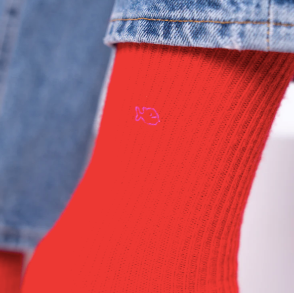 Red sock with a small logo worn with blue jeans.