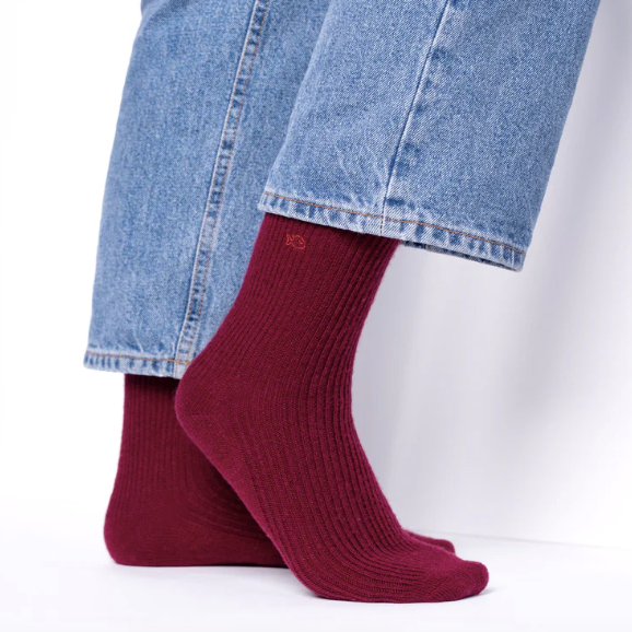 Burgundy socks worn with blue jeans on a white background