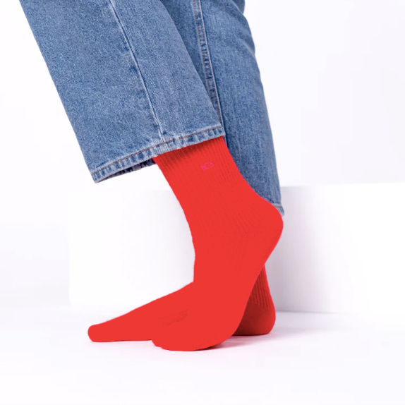 Red socks worn with blue jeans on a white background