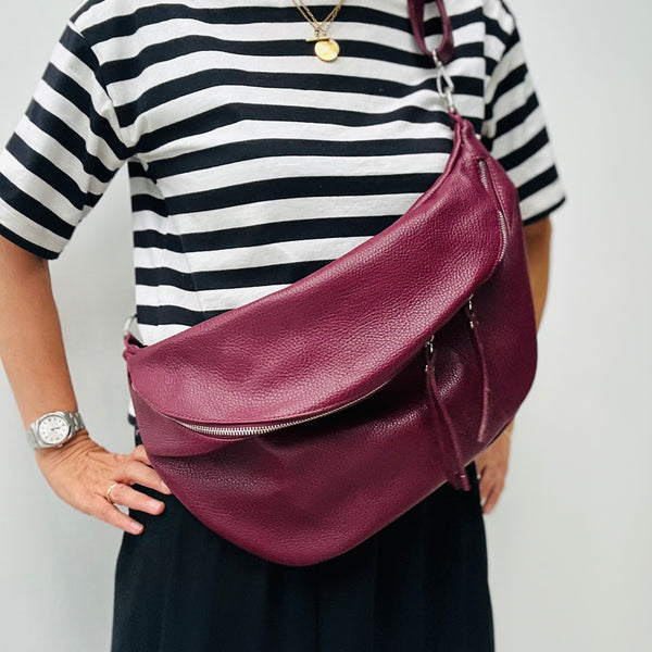 Cathy wearing the XL burgundy leather bag as a crossbody bag against a white background