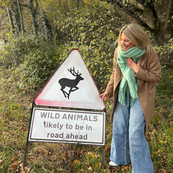 woman in a camel scarf and aqua blanket stitch scarf in the forest