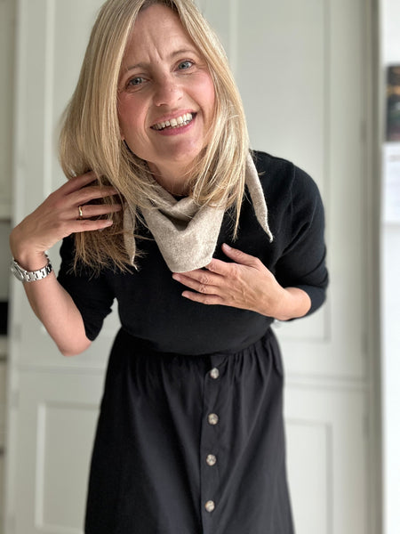 Woman wearing a black outfit with a beige scarf indoors