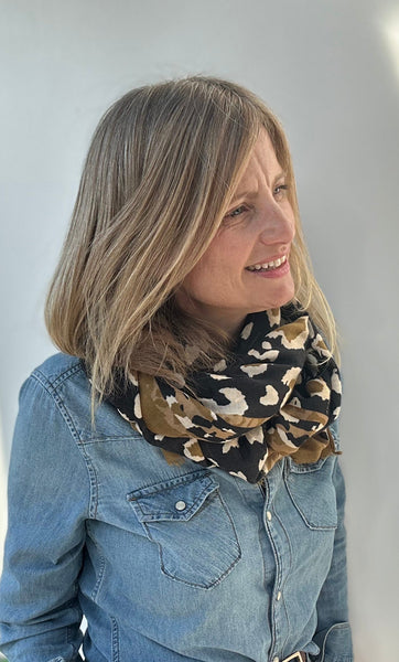 Woman wearing a denim jacket and leopard print scarf indoors