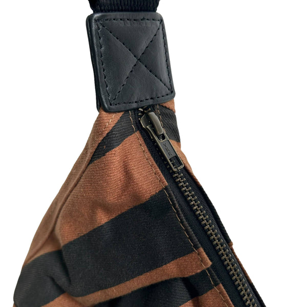Close-up of a brown and black striped fabric bag with a black strap and zipper, shown on a white background.