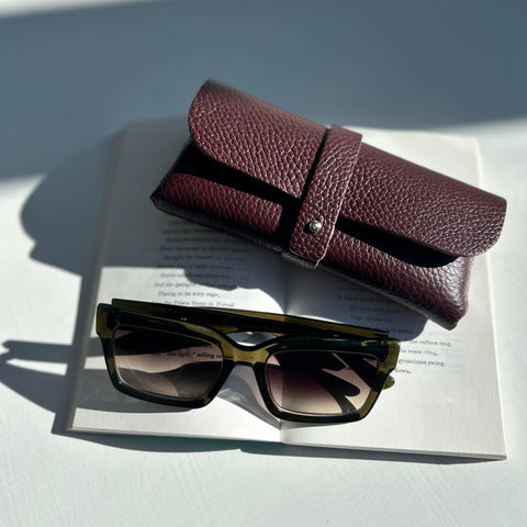 Sunglasses and brown leather case on an open book