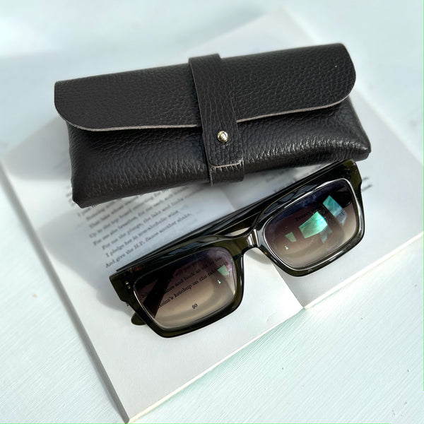 Chocolate Brown leather glasses case on a poetry book with green sunglasses