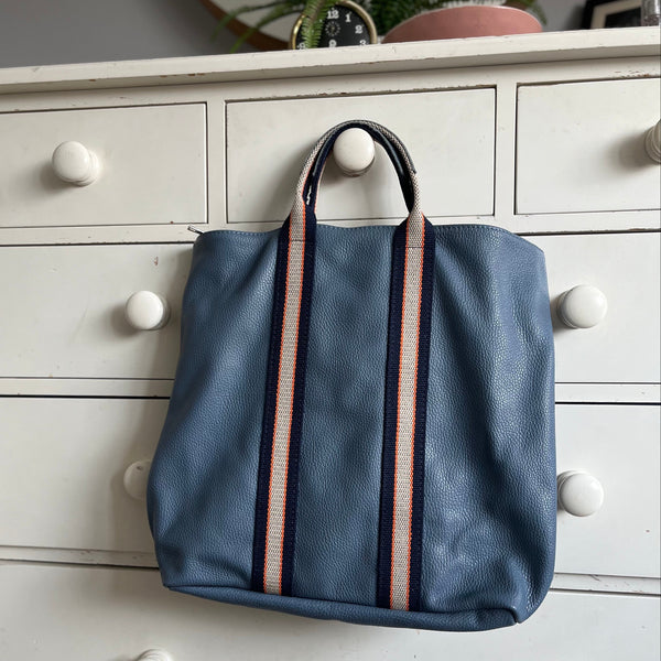 Denim Blue Leather Tote Backpack hanging on a cream wooden chest of drawers
