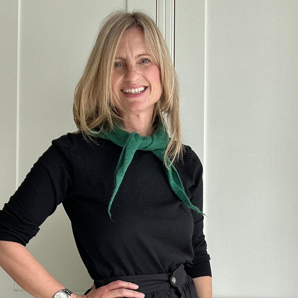 woman in black skirt and sweater with a forest green knotted scarf