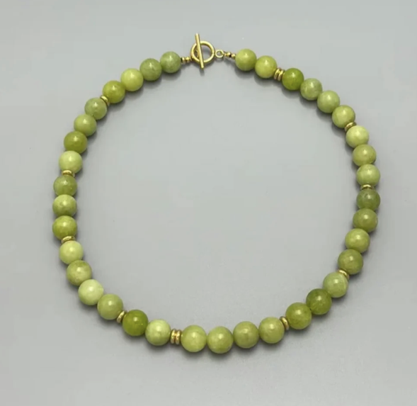 Green quartz beaded necklace with a gold t-bar clasp on a white background