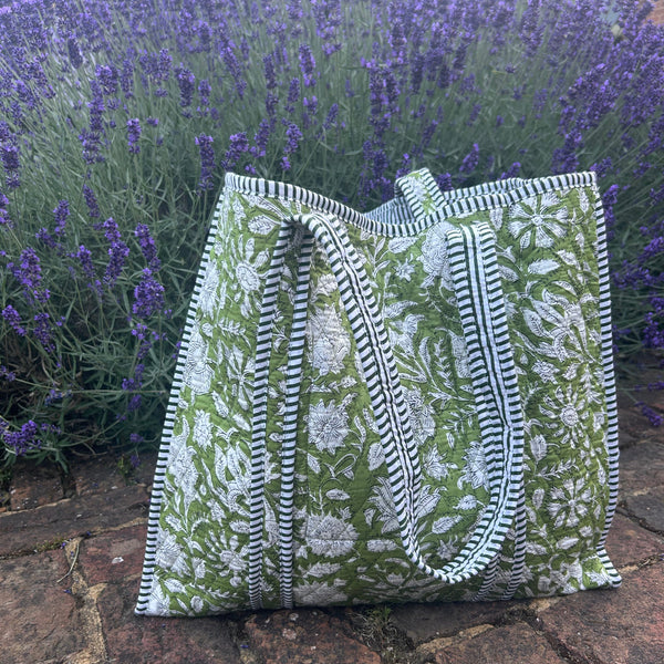 Green floral-patterned tote bag on a brick surface with lavender in the background