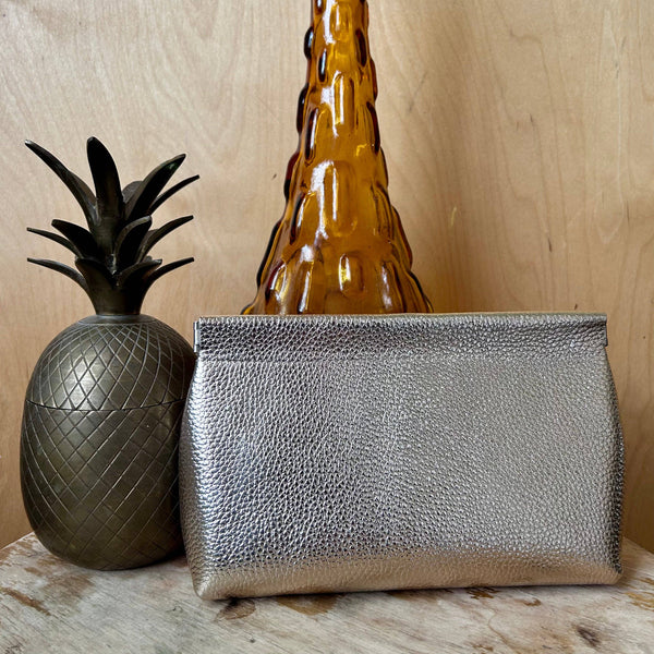 Gold clutch bag on a wooden surface with decorative items