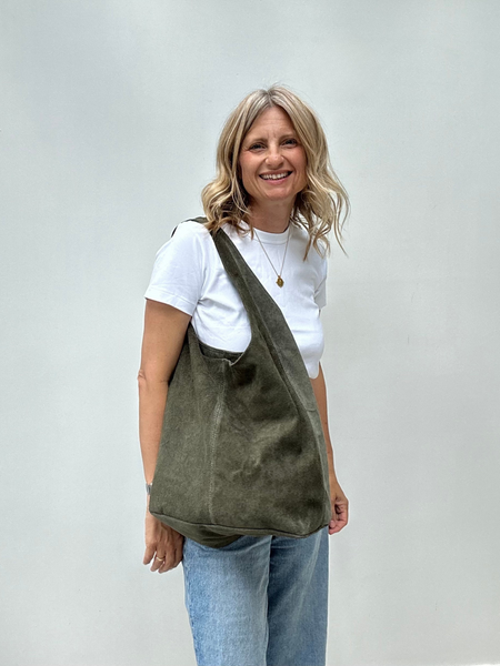 cathy carrying an olive green suede shoulder bag against a plain background